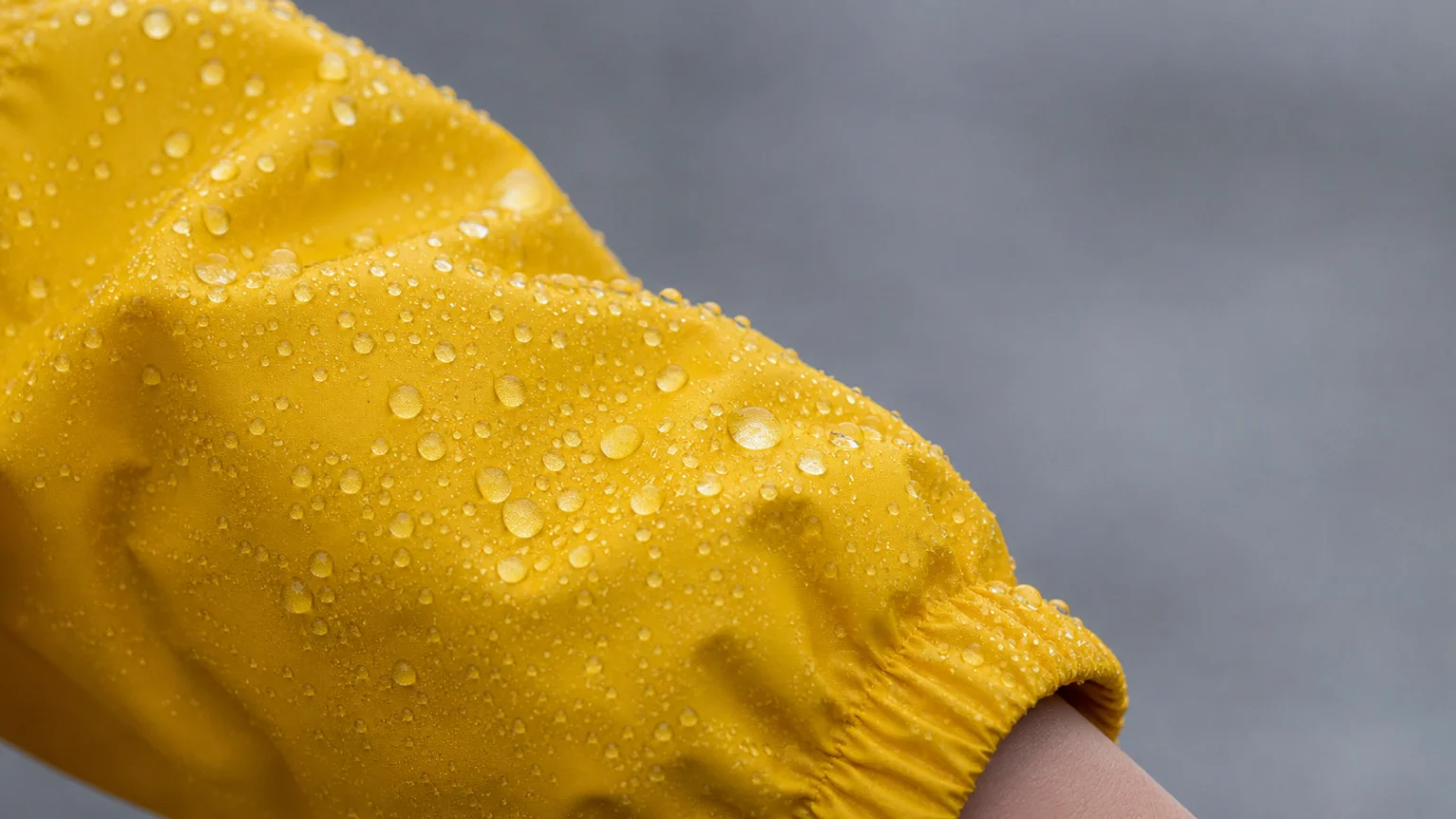 Gouttes d'eau perlant sur la manche d'un imperméable jaune d'enfant