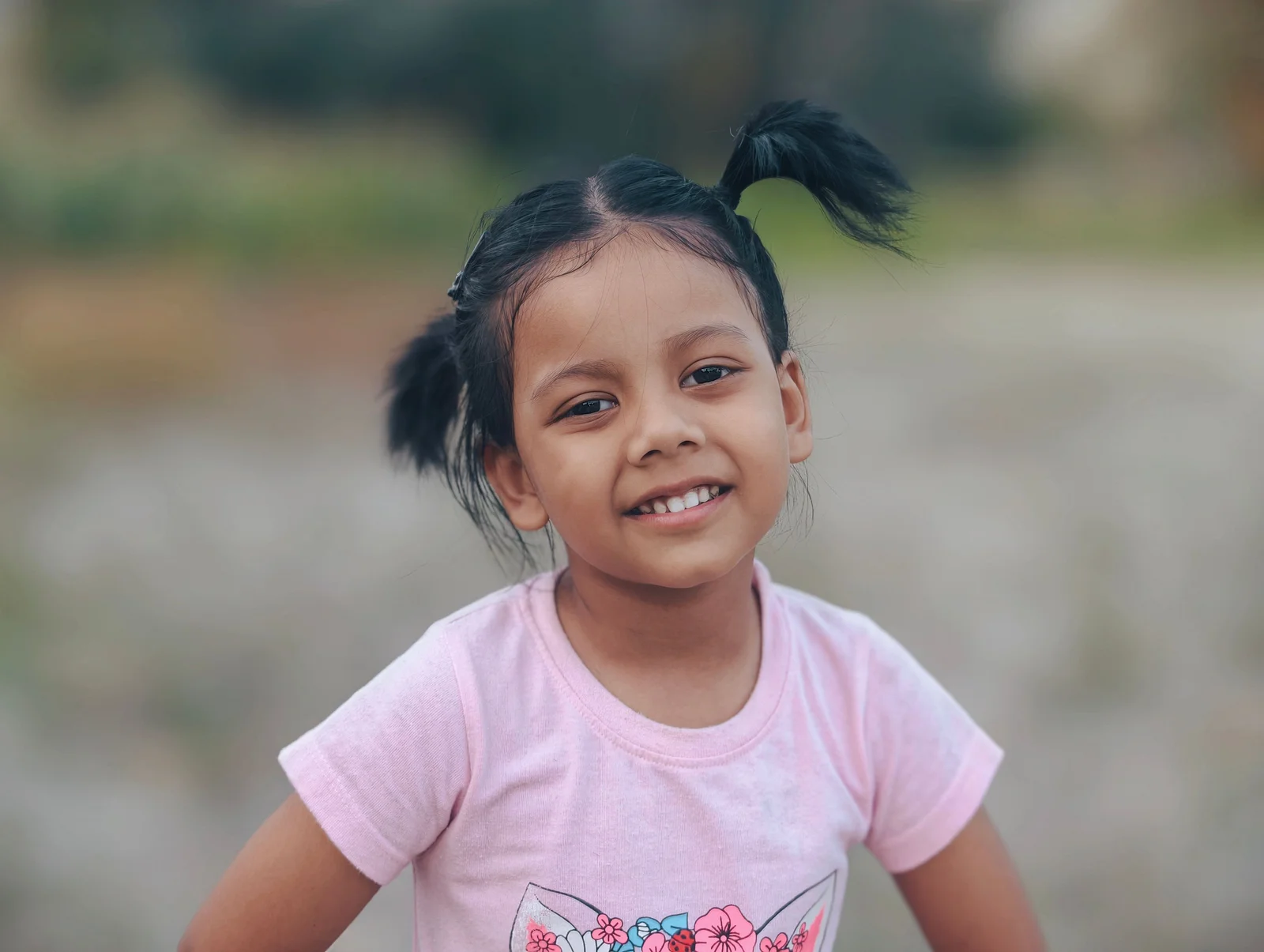 Petite fille aux cheveux bouclés coiffée en couettes hautes